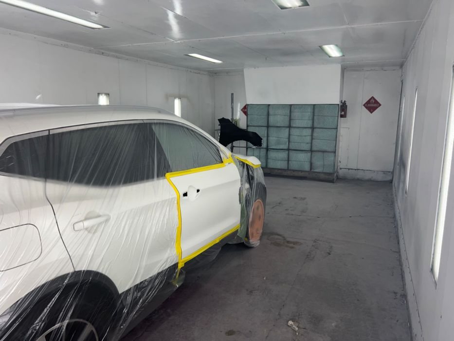 White SUV masked for paint in the prep area